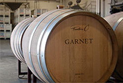 Large oak wine barrels in racks with Garnet logo on them
